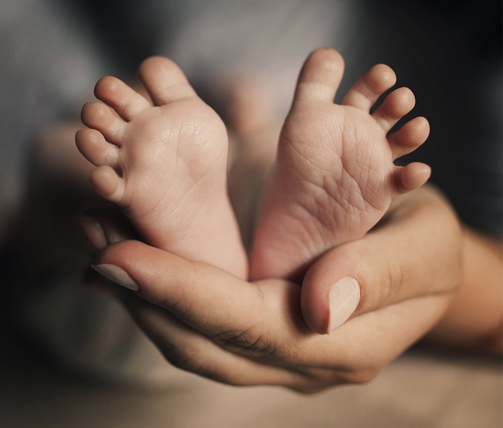 mother holding newborn baby's feet